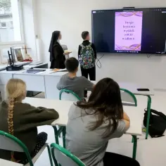 Nauczycielka w habicie i uczniowie patrzą na ekran z informacją o Drodze Krzyżowej. Czy religia liczy się do średniej?