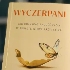 Okładka książki "Wyczerpani. Jak odzyskać radość życia w świecie, który przytłacza", z motylem na liściu.