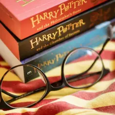 Okulary leżą na tle książek z serii Harry Potter, gotowe do kolejnej magicznej lektury.