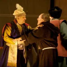 Dwóch mężczyzn w strojach teatralnych, jeden w barwnym, drugi w habicie, w dramatycznym uścisku. Czy szlachetnymi uczynkami można odkupić ciężką winę?
