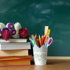 Kwiaty na stosie książek i przybory szkolne. Czy dzień nauczyciela jest dniem wolnym?