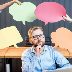 Mężczyzna w okularach zastanawia się nad opiniami klientów, otoczony kolorowymi dymkami.