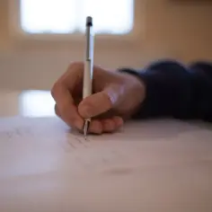 Dłoń pisze na kartce, przygotowując się do przemówienia na egzamin ósmoklasisty.