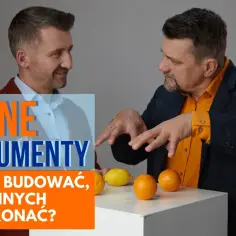 Dwóch mężczyzn dyskutuje, jak konstruować silne argumenty. Na stole leżą owoce, symbolizujące różne punkty widzenia.