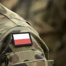 Żołnierz w mundurze moro z naszywką z polską flagą. Po studiach wojskowych zdobywa swój pierwszy stopień wojskowy.