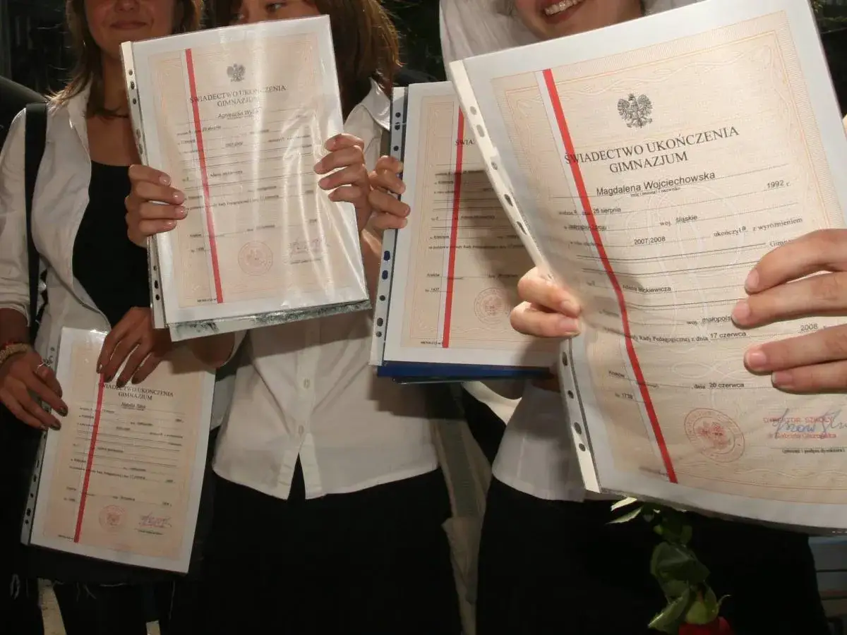 Uczniowie z dumą prezentują świadectwa ukończenia gimnazjum. Widać daty ukończenia, od jakiej średniej jest pasek i nazwiska absolwentów.