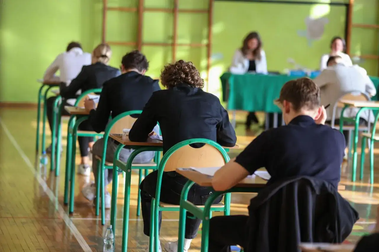 Uczniowie piszą egzamin, który zdecyduje, jak liczy się punkty na studia. W tle widać nauczycieli.