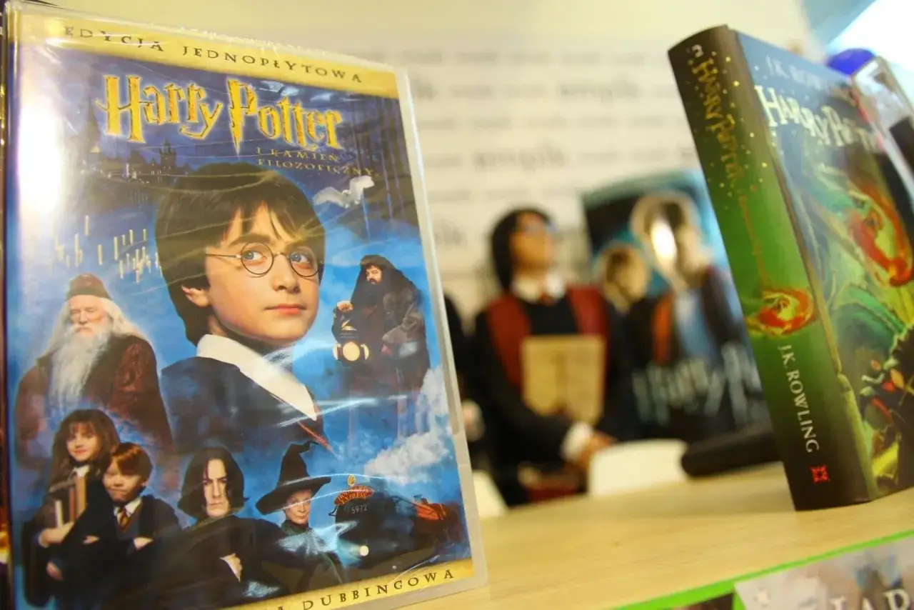 Harry Potter lektura: okładka filmu z młodym Harrym, Dumbledorem, Hagridem i innymi, obok książka J.K. Rowling.