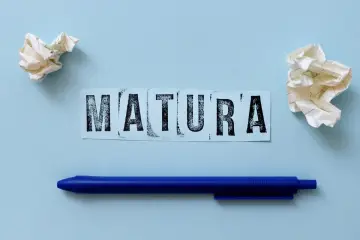 Napis "MATURA" na niebieskim tle, obok kulki papieru i długopis. Zastanawiasz się, ile trwa matura z polskiego?