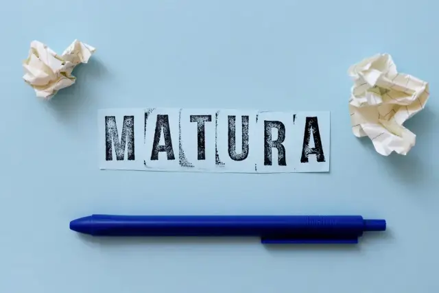 Napis "MATURA" na niebieskim tle, obok kulki papieru i długopis. Zastanawiasz się, ile trwa matura z polskiego?